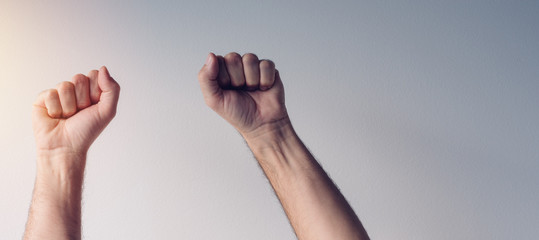 Clenched fists and arms raised in victorious manner