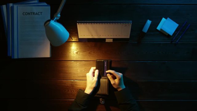 A man is sitting at an office desk and using a phone.