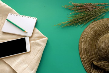 Business woman relaxing on vacation with hat ,note,smart phone and white fabric on green background
