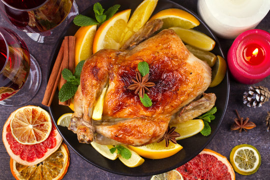 Chicken or turkey with lemons, oranges, limes and spices on Christmas and New Year background. Top view, horizontal