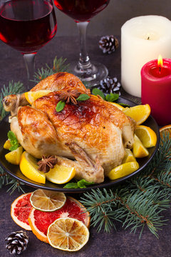 Chicken or turkey with lemons, oranges, limes and spices on Christmas and New Year background. Two glasses of wine, vertical
