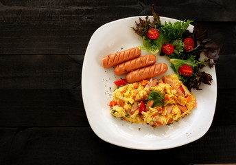 Omelette  with onion, tomatoes,sausage and fresh salad wooden spoon and fork  on white plate