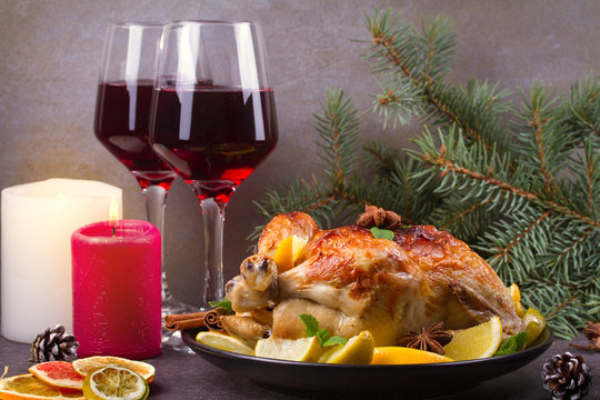 Chicken or turkey with lemons, oranges, limes and spices on Christmas and New Year background. Two glasses of wine, horizontal