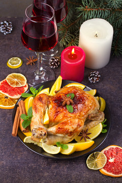 Chicken or turkey with lemons, oranges, limes and spices on Christmas and New Year background. Two glasses of wine, vertical