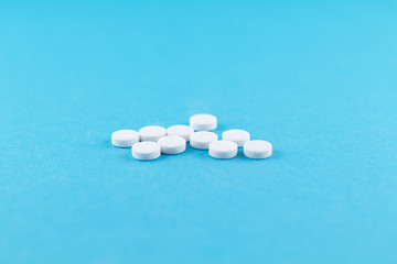 White pills with copy space on blue background. Focus on foreground, soft bokeh