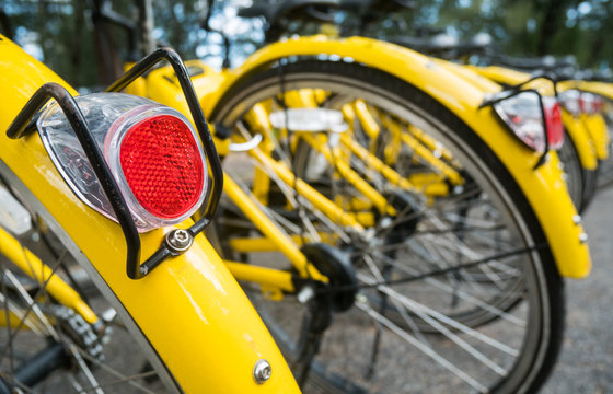 Close up Bicycle tail light on group of yellow vintage bike parking in the Park to service the touristi n bike sharing concept.