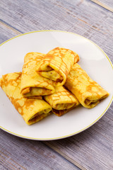 Wrapped thin pancakes  filled with mushrooms on white plate, vertical