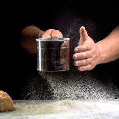 hand sift the flour on black background