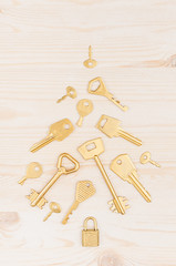 Christmas tree of gold keys on soft beige wooden background.