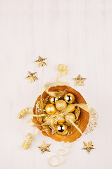 Christmas decorations, gold stars, balls and ribbons on soft white wooden background, copy space. Top view, vertical.