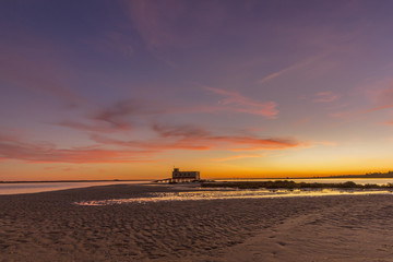 Fototapeta premium Dusk and historic life-guard building at Fuseta fishing town, in Ria Formosa wetlands nature conservation park, Algarve. Portugal.