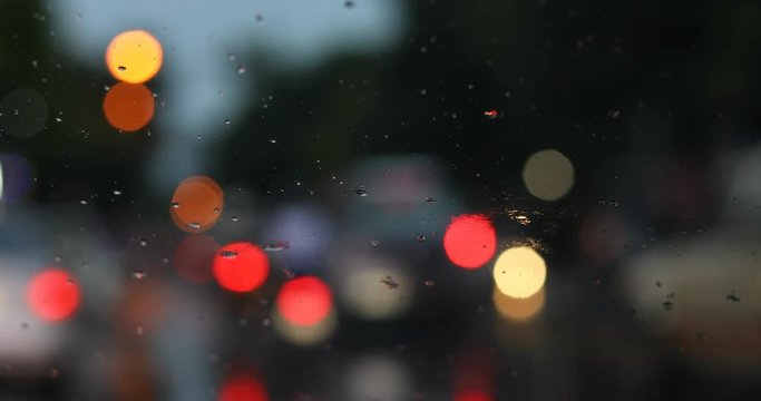rain drop on windshield with blur light of vehicle car traffic jam urban road in the city