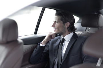 Fototapeta na wymiar successful man sitting in the back seat of a car