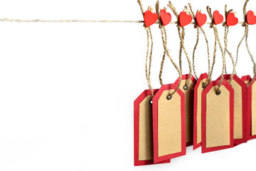 Red and brown paper tags hanging on the rope by heart shape pins with copy space isolated on white background. St. Valentine's gift concept.