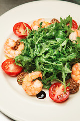 Dish with rocket salad, tomato and shrimp, pieces of meat