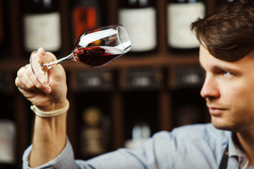 Bokal of red wine on background, male sommelier appreciating drink