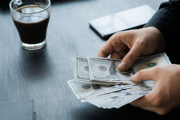 The white young Businessman counts the money, one hundred dollar bills on a black background close plan, Motion blur. Concepts of business and finance. top view 