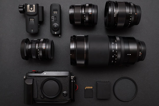 top view of photographer work space with mirrorless camera system, prime lens,telephoto zoom lens,battery,memory card and lens protection filter on black desk