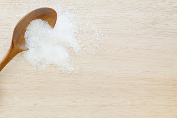 White sugar in wooden spoon on wooden table