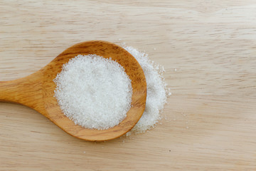 White sugar in wooden spoon on wooden table