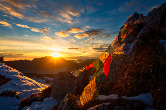 Flags of Tibetan prayers in the mountains with the colors of a warm sunset