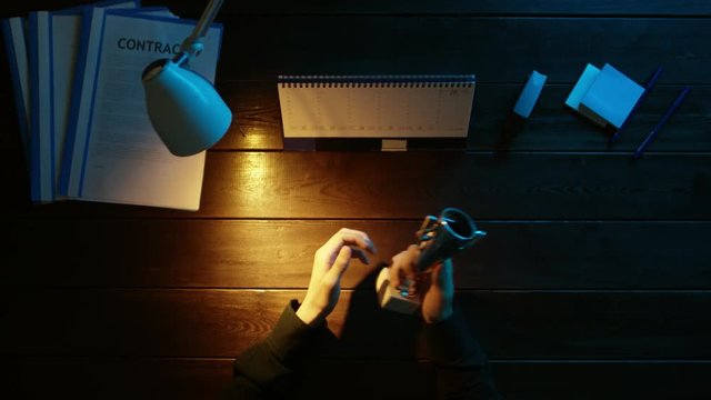 A man is sitting at an office desk and using a phone.