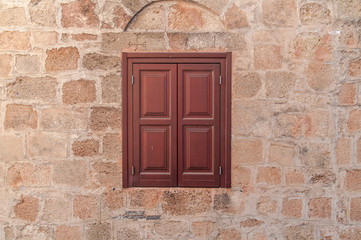 Red frame of one modern wooden window on yellow castle aged house wall