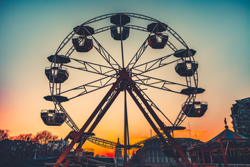 Ferris wheel Silhouette at sunset against the colorful evening skyline at dusk - popular children attraction in park. Vintage retro toning filter