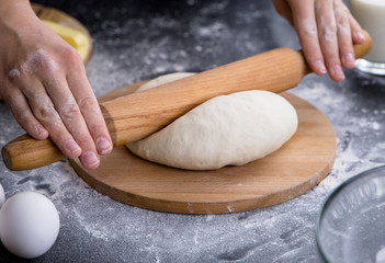 Making dough by female hands on wooden table background