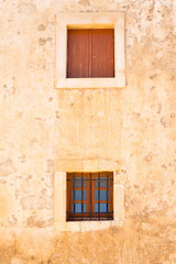Fototapeta na wymiar Two wooden windows on the yellow limestone wall