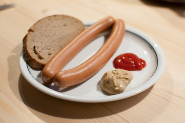 sausages on plate with bread ketchup and mustard