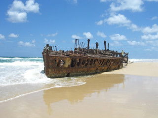 rusty shipwreck on the beach with blue sky