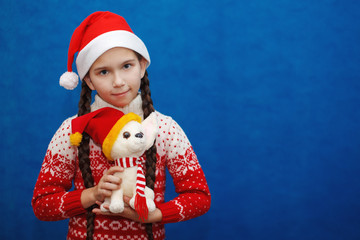 Little girl Santa celebrates Christmas with a toy dog Husky