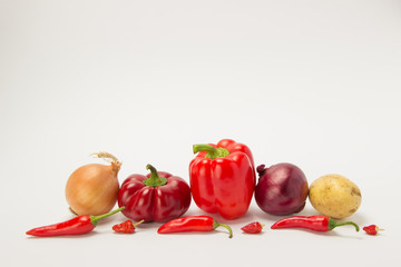 Several ripe sweet and hot peppers with parsley and dill on white background