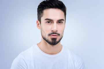 Fototapeta premium Calm. Bearded handsome young man looking calm and peaceful while standing against the blue background and looking straight