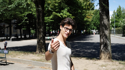 Young man in glasses standing in park and challenging to come closer and fight. 