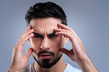 Very concentrated. Smart qualified tired worker doing his best to concentrate on the problem while touching the face with all his fingers