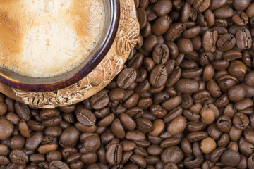 Coffee with foam in a cup on coffee beans