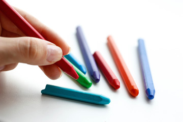 Hand holding colored crayons. Isolated on a white background. Closeup