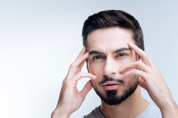 Intense thinking. Smart enthusiastic young specialist standing with his fingers on the forehead...