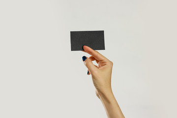 Female hands holding a black sheet of paper. Isolated on gray background. Closeup