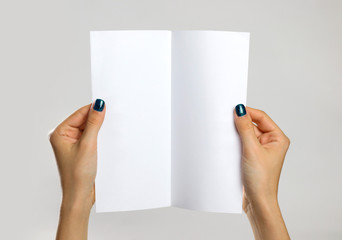 Female hands holding a white sheet of paper. Isolated on gray background. Closeup