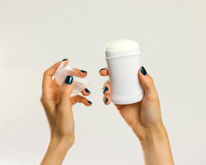 Female hands holding white deodorant. Isolated on gray background. Closeup
