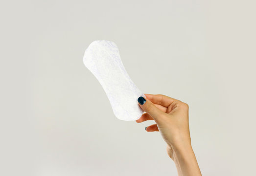 Female Hands Holding A White Sanitary Pad. Isolated On Gray Background. Closeup