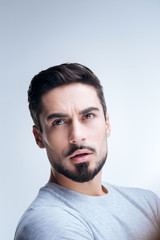 Obraz premium Suddenly. Young bearded handsome man feeling surprised while staring at the sky with his mouth opened and watching a huge helicopter landing not far from him