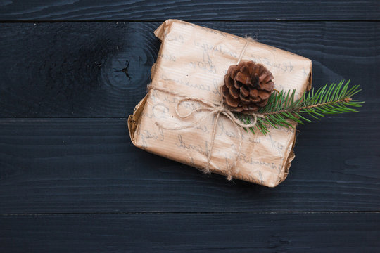 Wrapping rustic eco Christmas packages with brown paper, string and natural fir branches on dark background. Flat lay, free space.