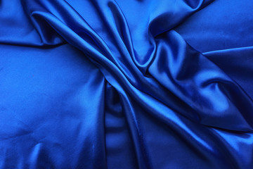 Blue satin, silky fabric, wave, draperies. Beautiful textile backdrop. Close-up. Top view 