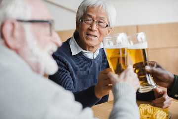 senior friends clinking glasses of beer