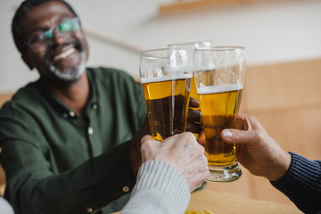man clinking glasses of beer with friends