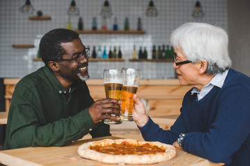 senior friends clinking glasses of beer